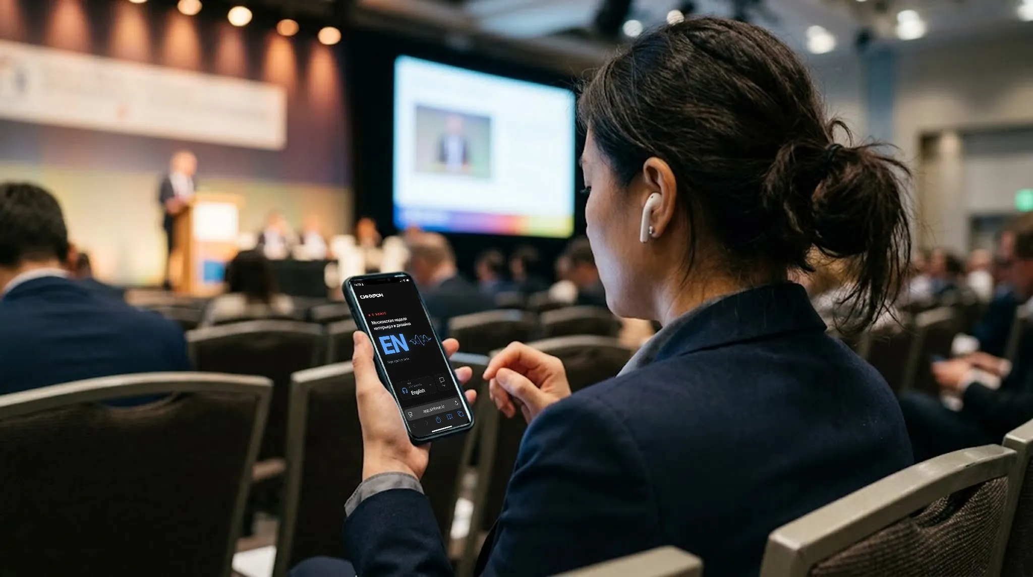 A delegate in the hall listens to the interpretation on her phone