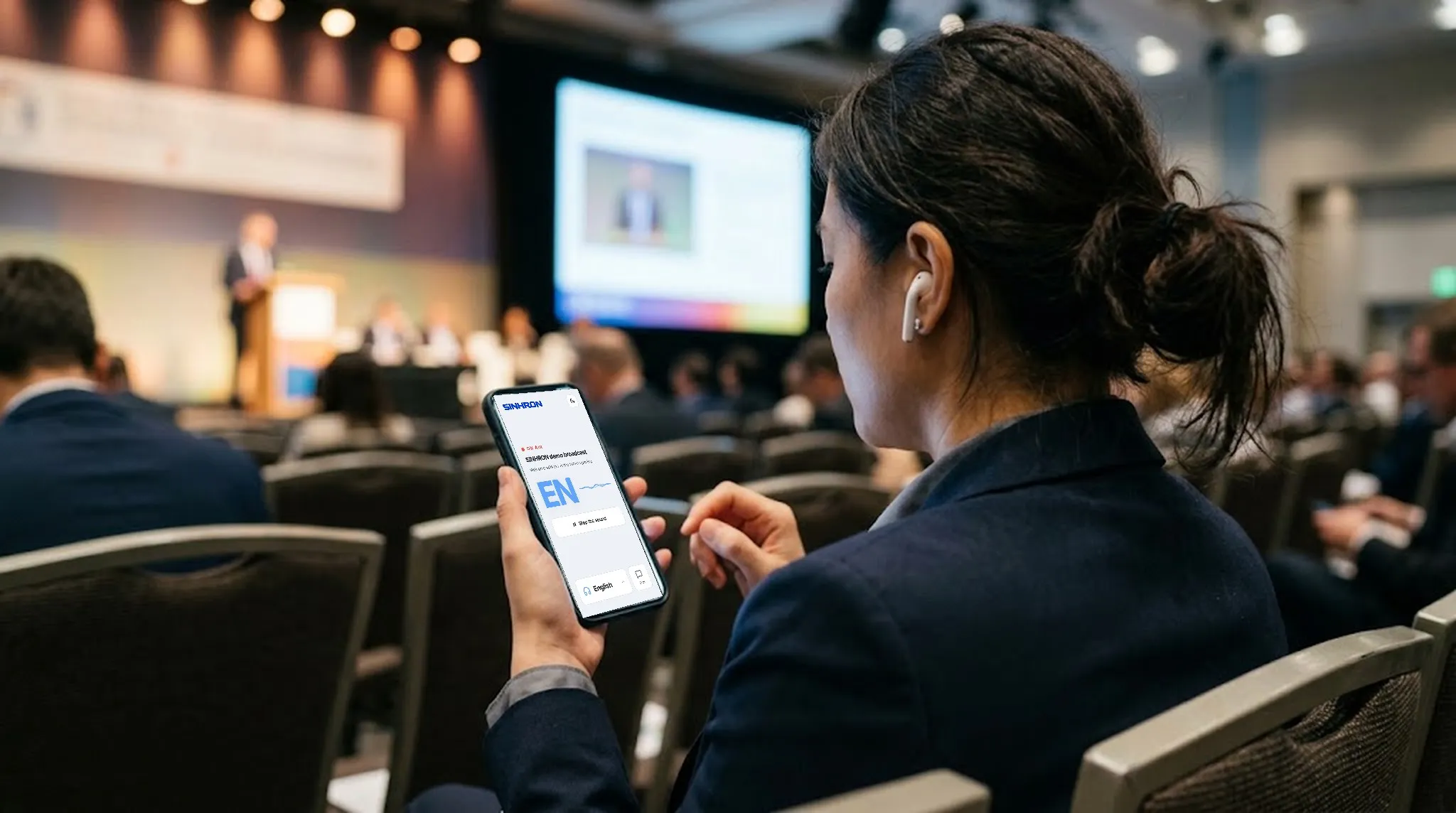Une déléguée dans la salle écoute l'interprétation sur son téléphone